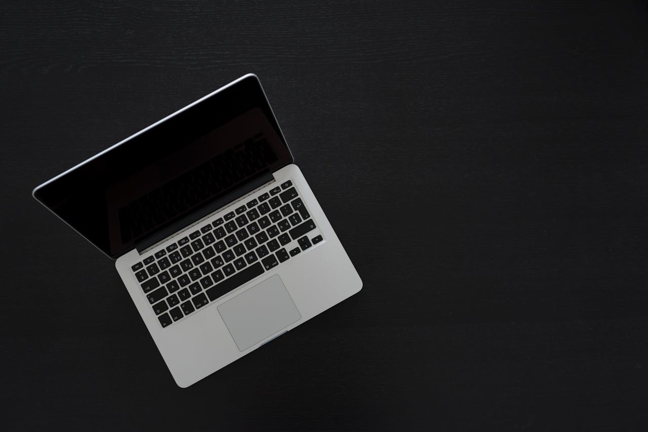 Overhead view of a MacBook laptop on a dark desk, showcasing modern technology and minimalism.